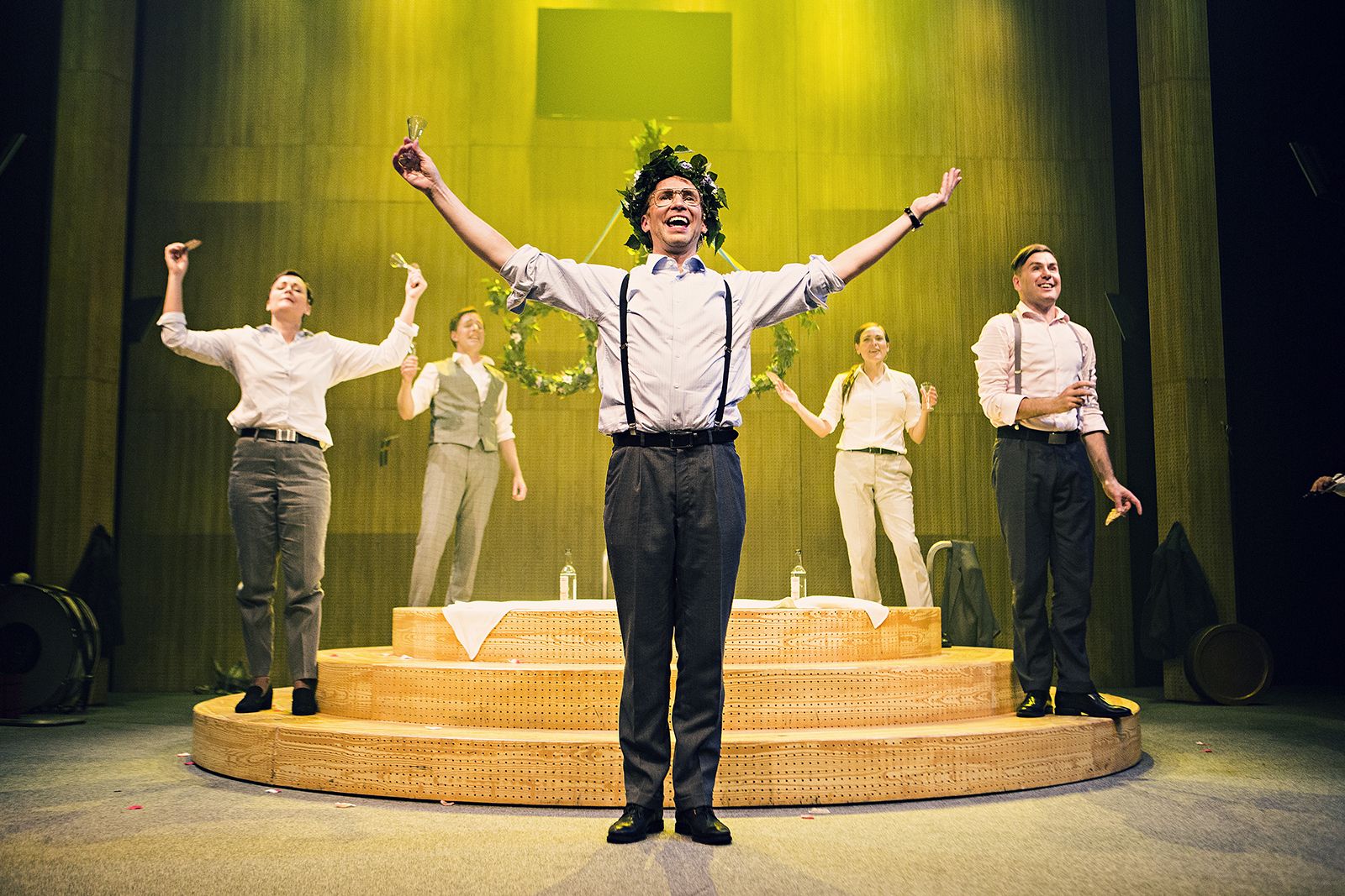 Fem personer står på en teaterscen och sträcker ut händerna i luften